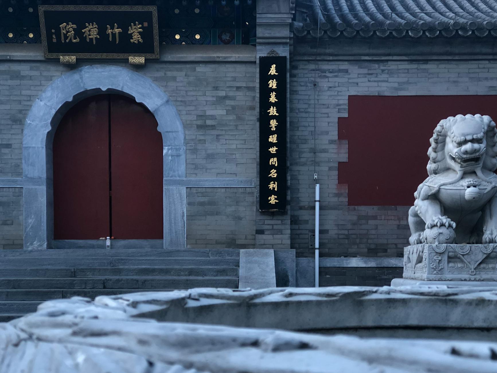 Red gate entrance to a traditional Beijing temple with lanterns