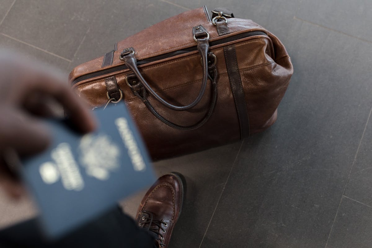 Brown leather travel bag with passport at airport for international trip