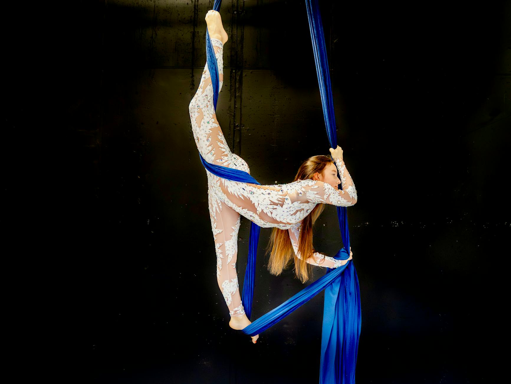 Graceful aerialist performing on blue silk