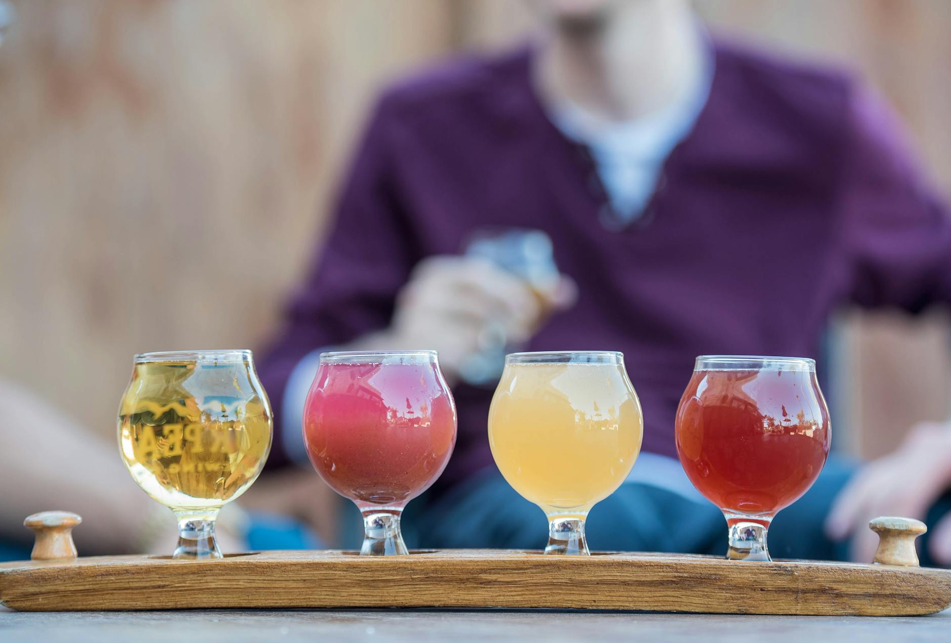 A flight of craft beers in glasses on a wooden table
