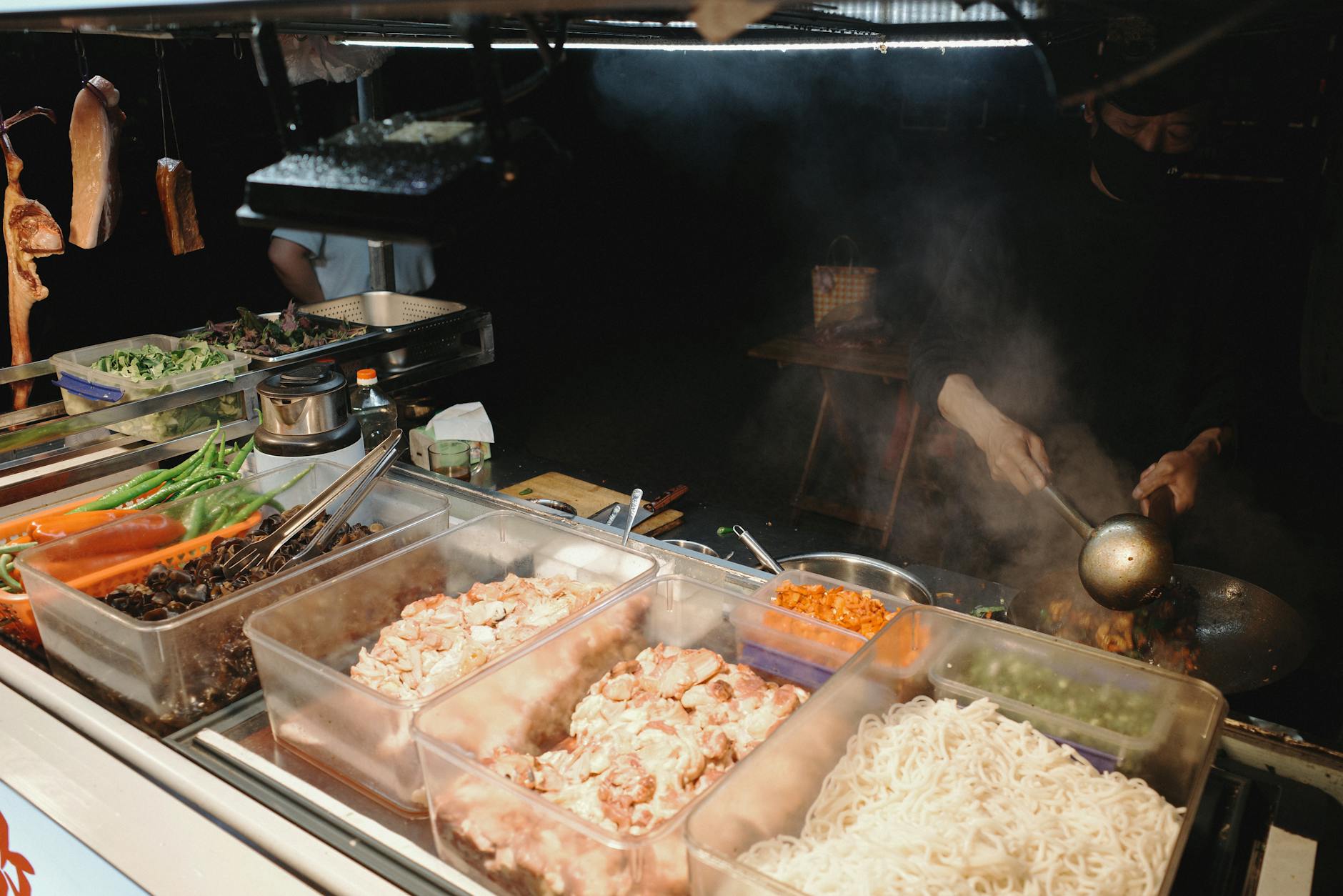 Bustling night-market food stall with many ingredients