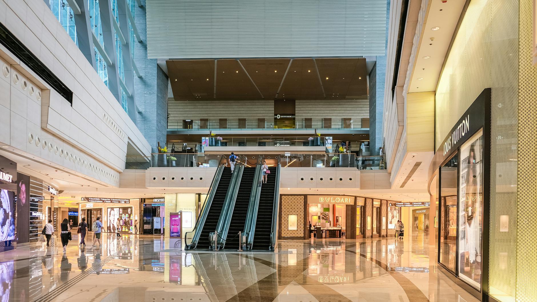 Modern shopping mall interior with escalators and luxury stores