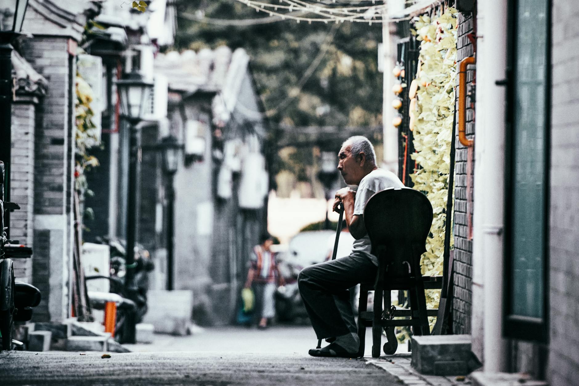 An elderly man sitting quietly in a Beijing alley