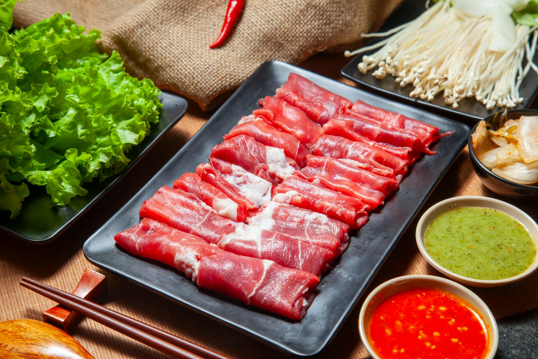 Fresh hot pot ingredients including thinly sliced beef and vegetables