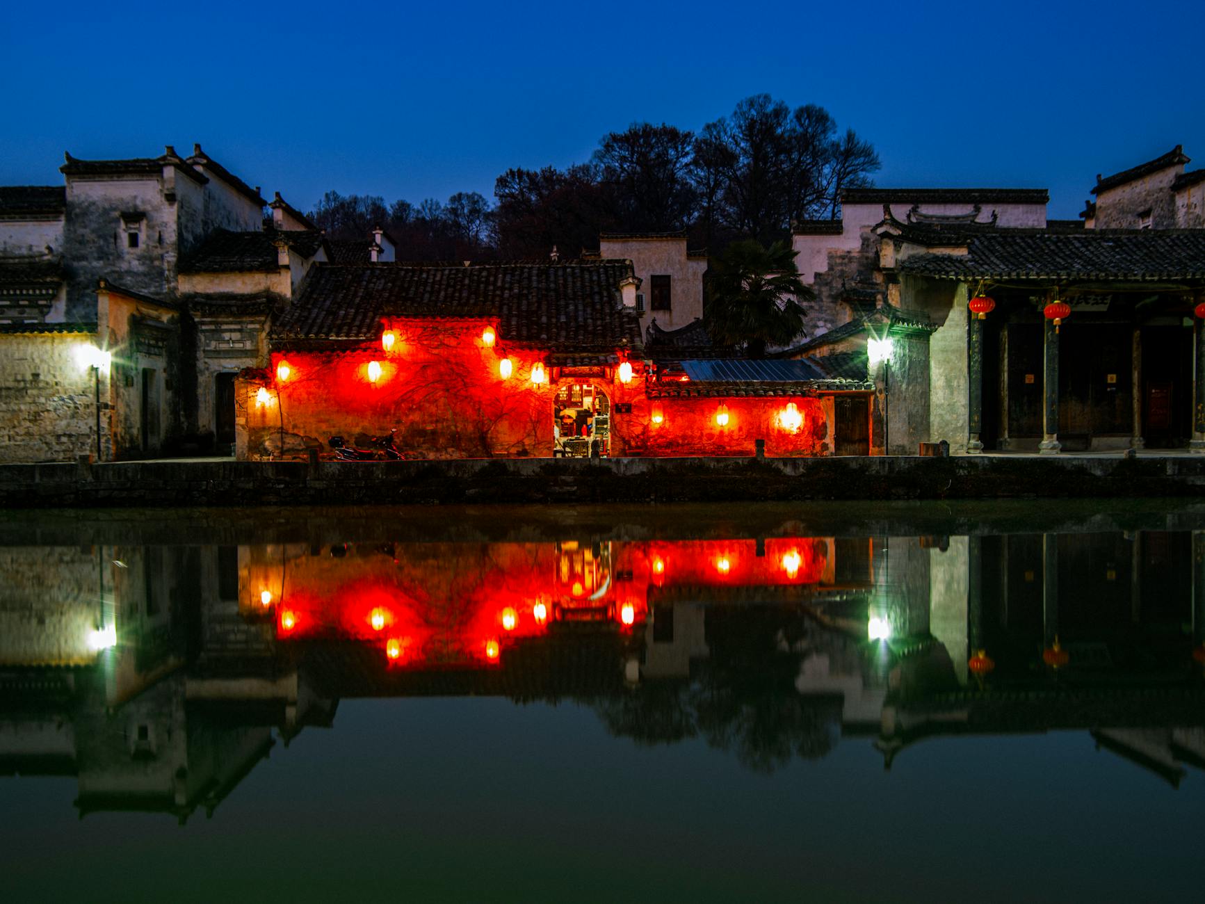 Illuminated traditional Chinese building reflecting on water