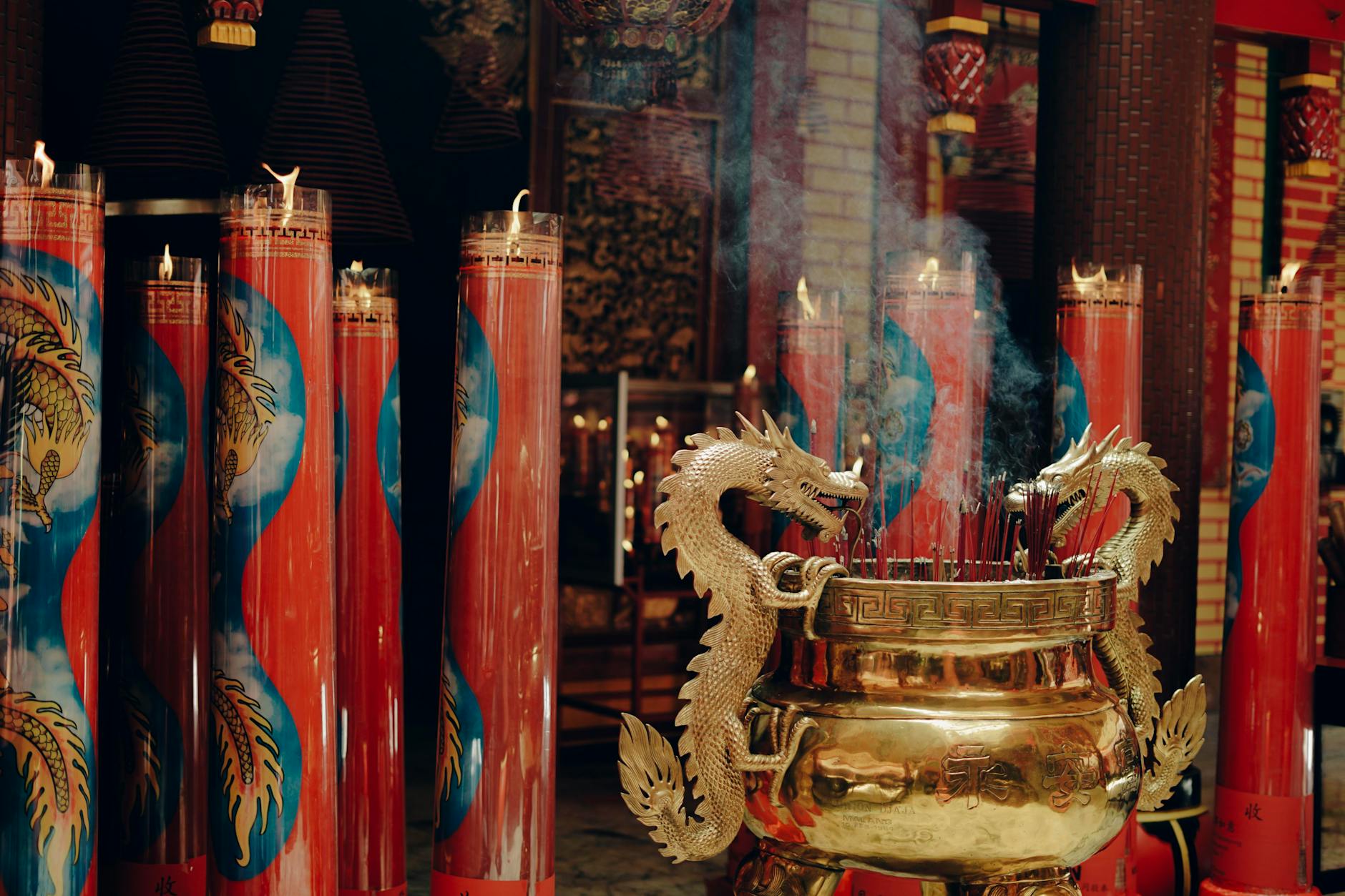 Incense sticks and candles burning before a golden temple shrine