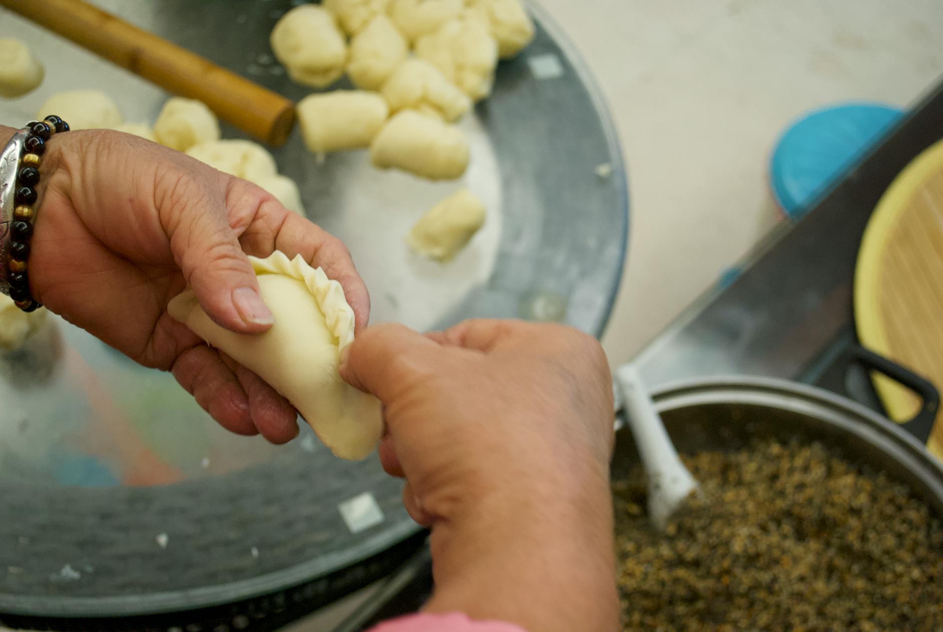 Close-up of hands shaping fresh dumplings