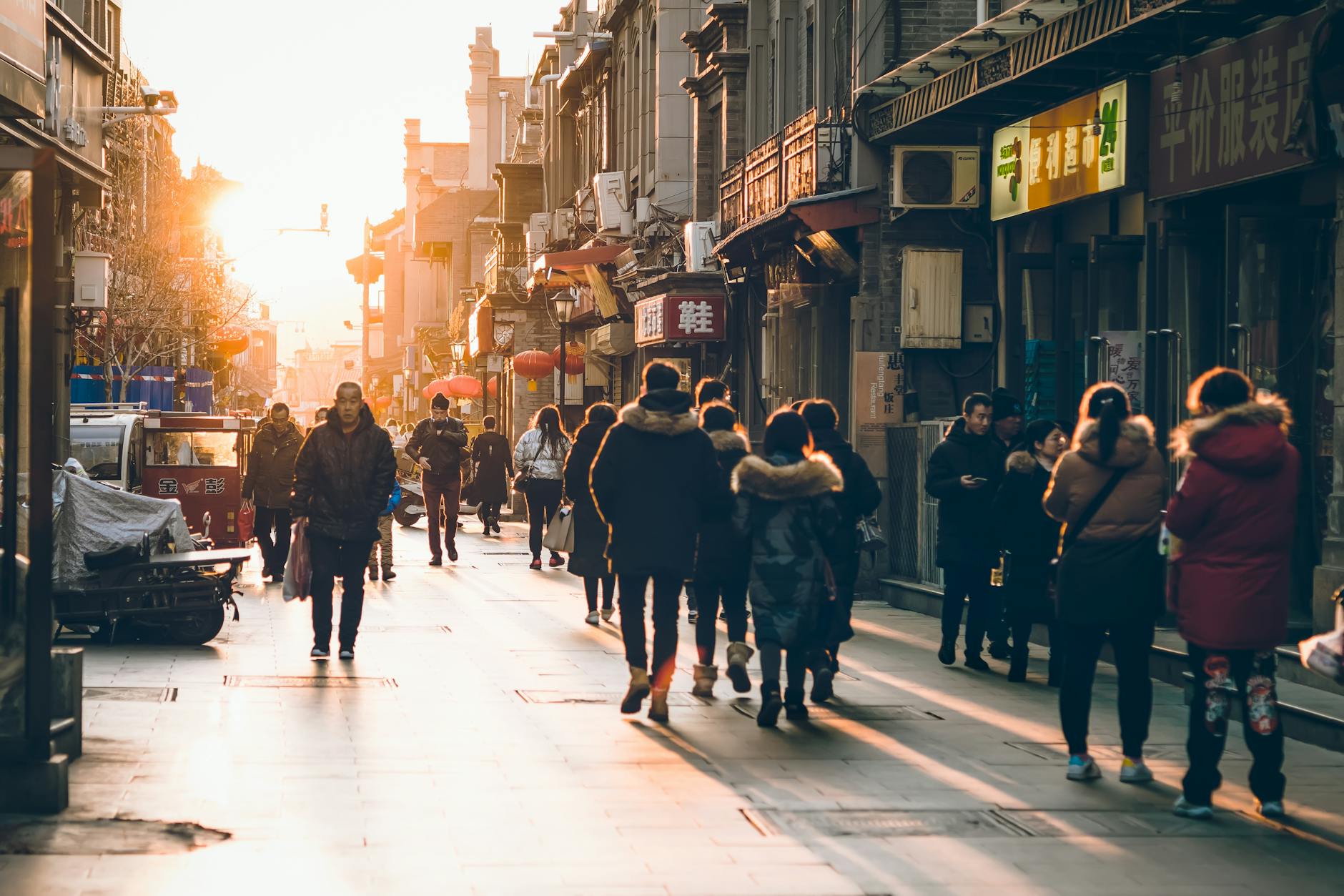 People walking a vibrant Beijing street at sunset