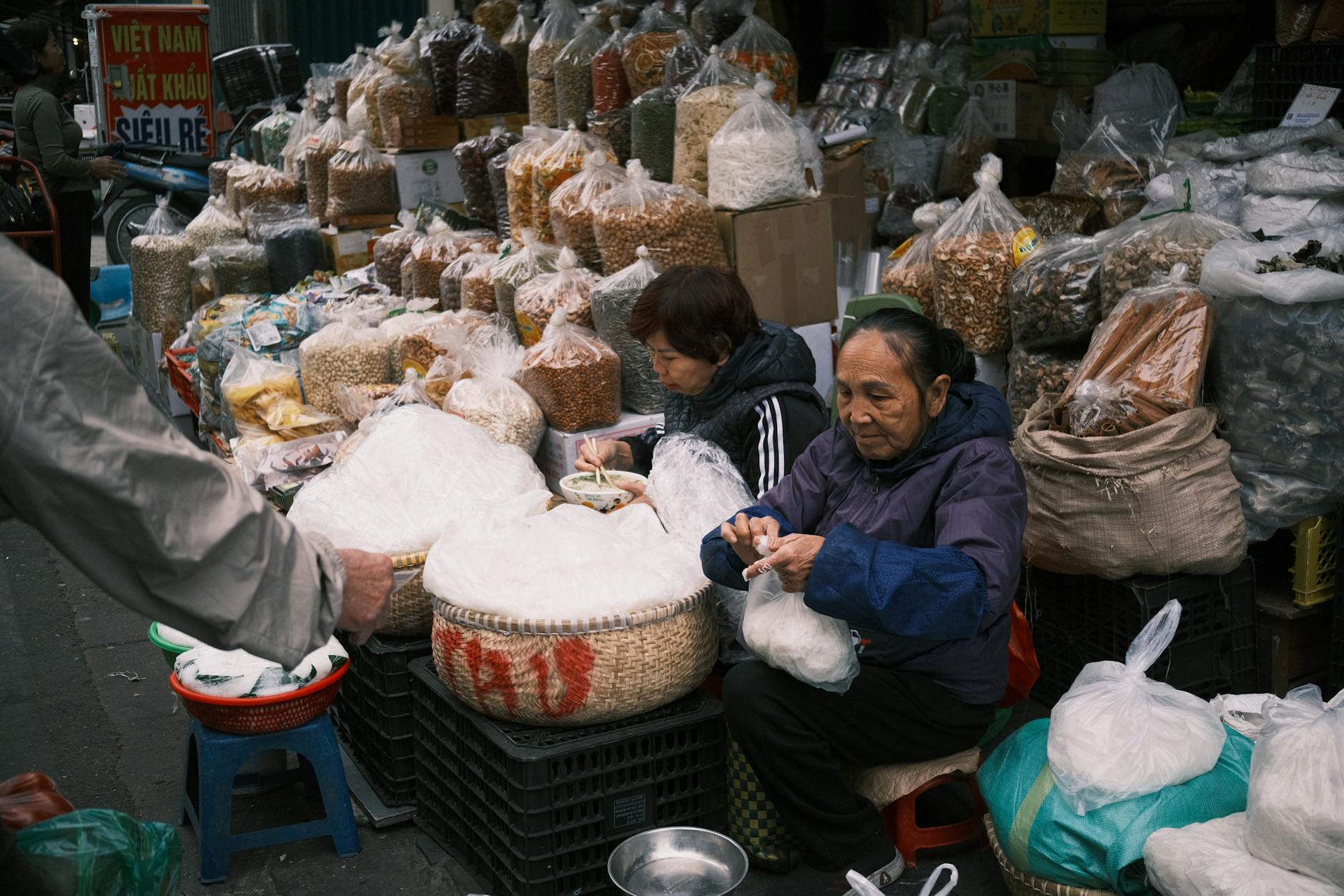 Women working at an outdoor market stall full of goods