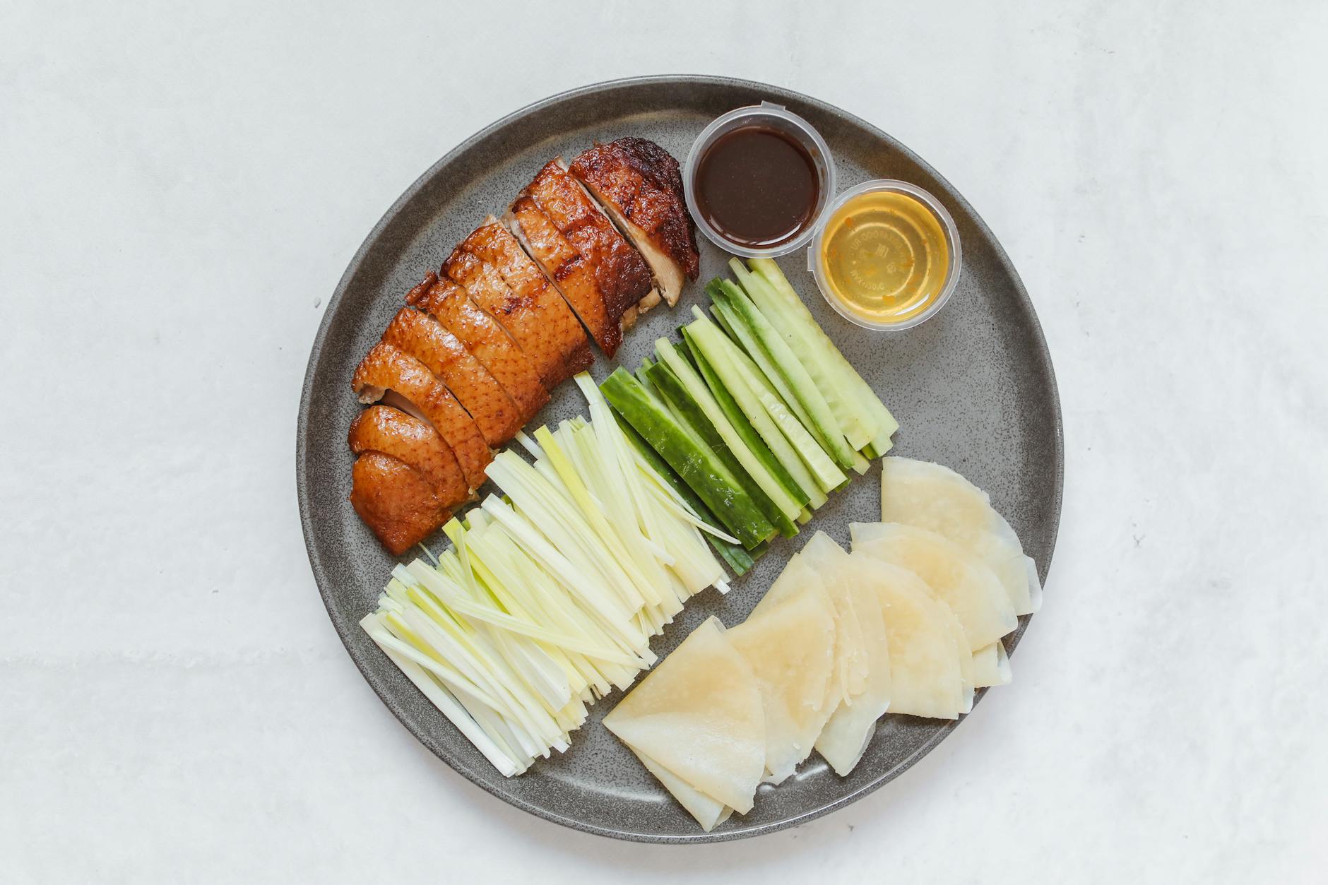 Plate of sliced Peking duck with cucumber, scallions and pancakes