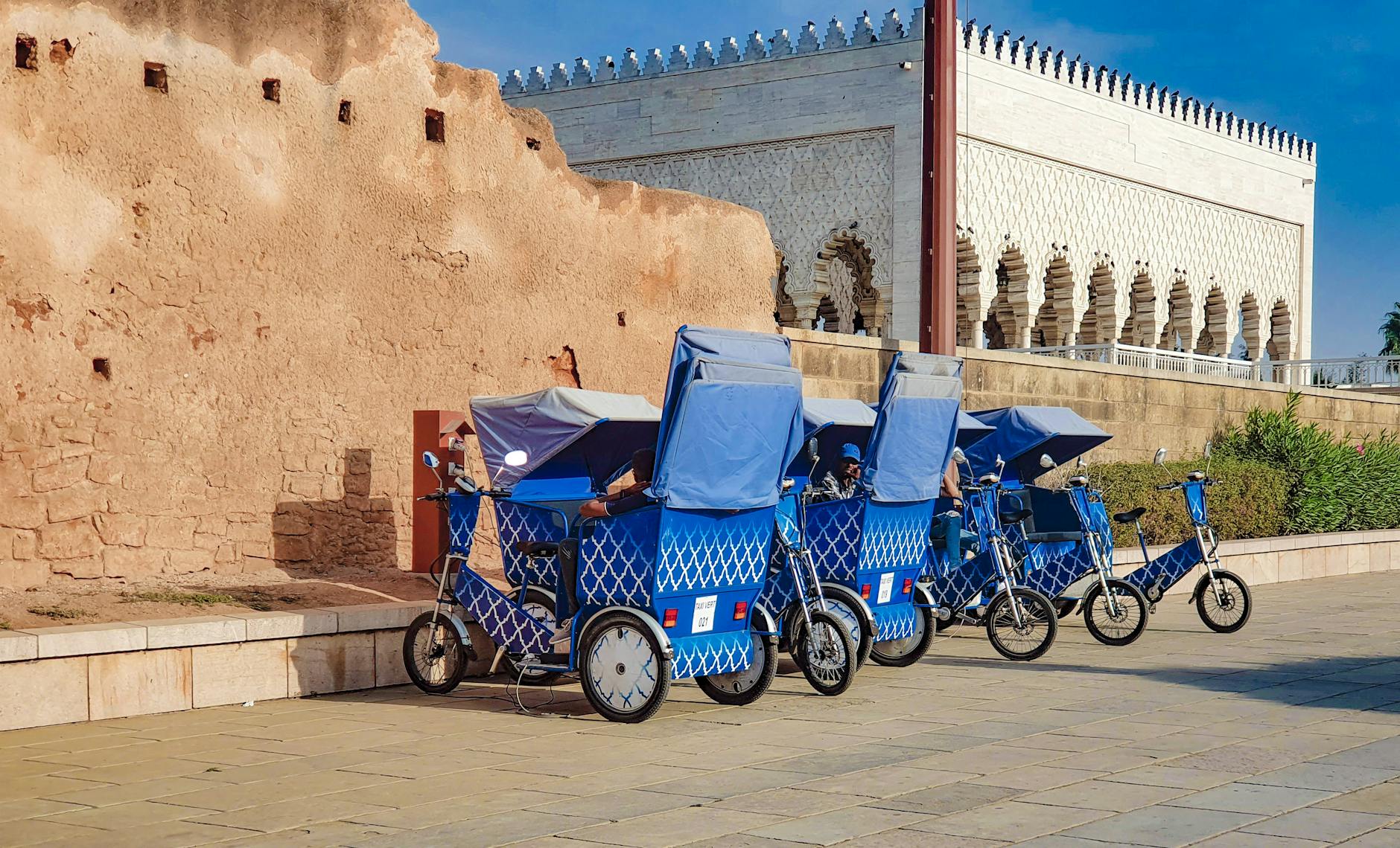 Rickshaws lined up beside a historic stone wall