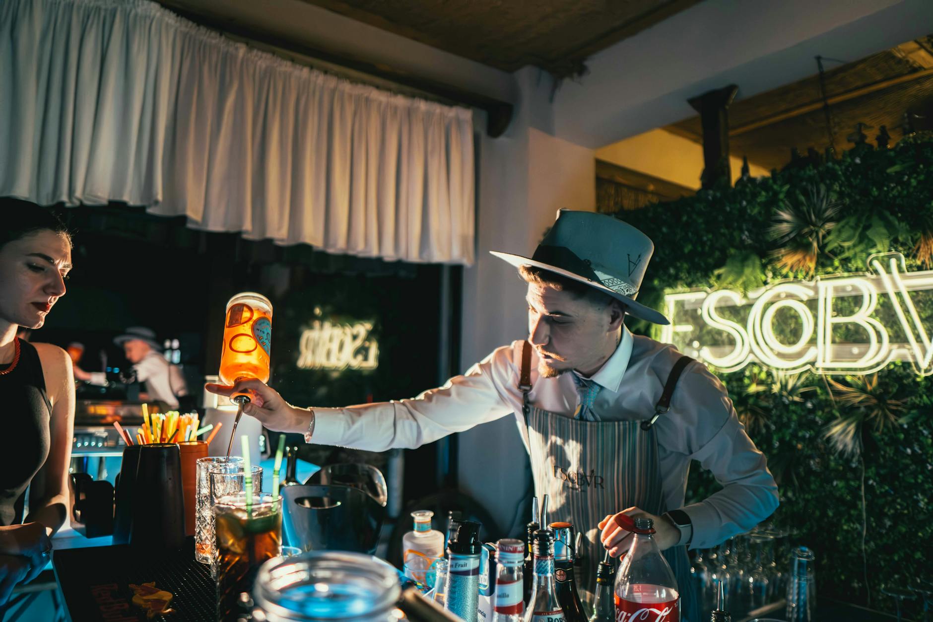 Bartender mixing a cocktail in a trendy neon-lit bar