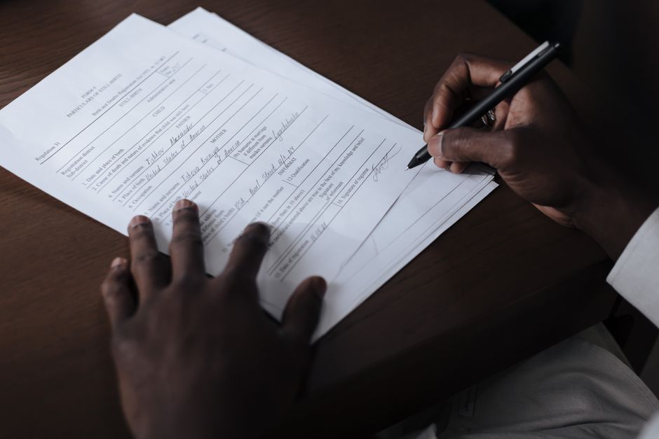 Person signing official visa application documents at a desk