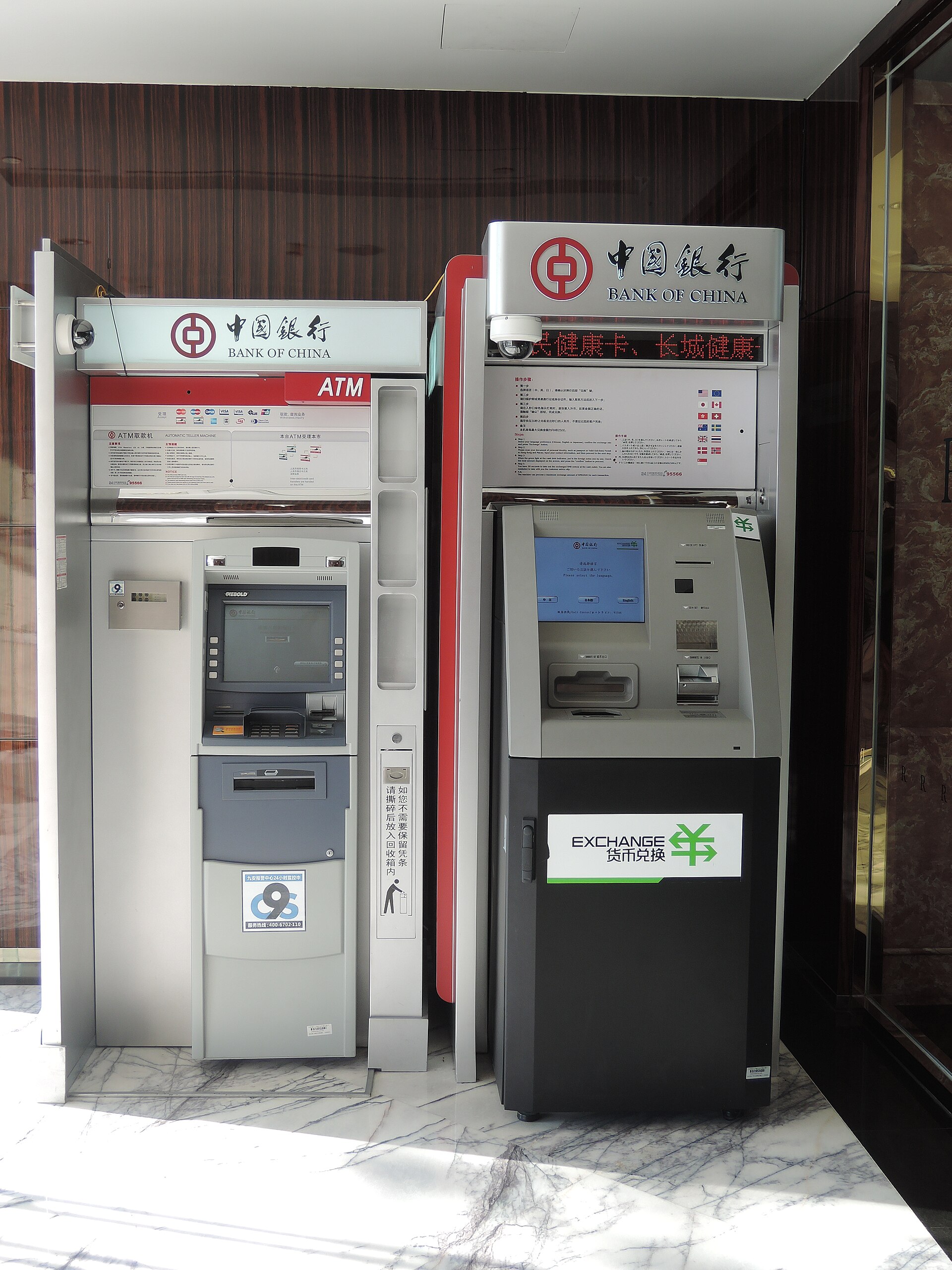 A Bank of China ATM beside a foreign-currency exchange machine in a marble-floored bank lobby