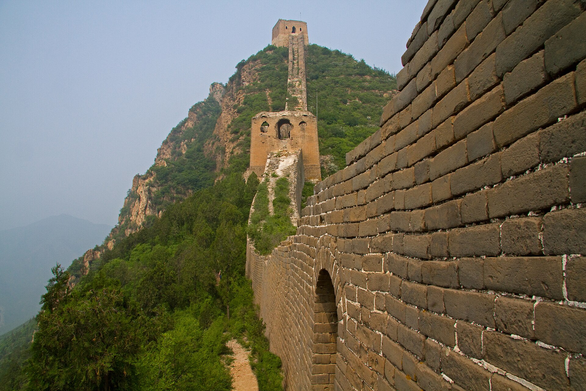 An empty ruined stretch of Great Wall at Gubeikou climbing towards a collapsed watchtower with no people in sight