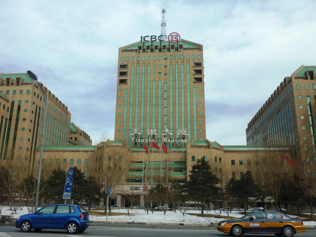 ICBC's Tianyin Mansion office building in Beijing on a snowy winter day, with a yellow and blue city taxi passing in front