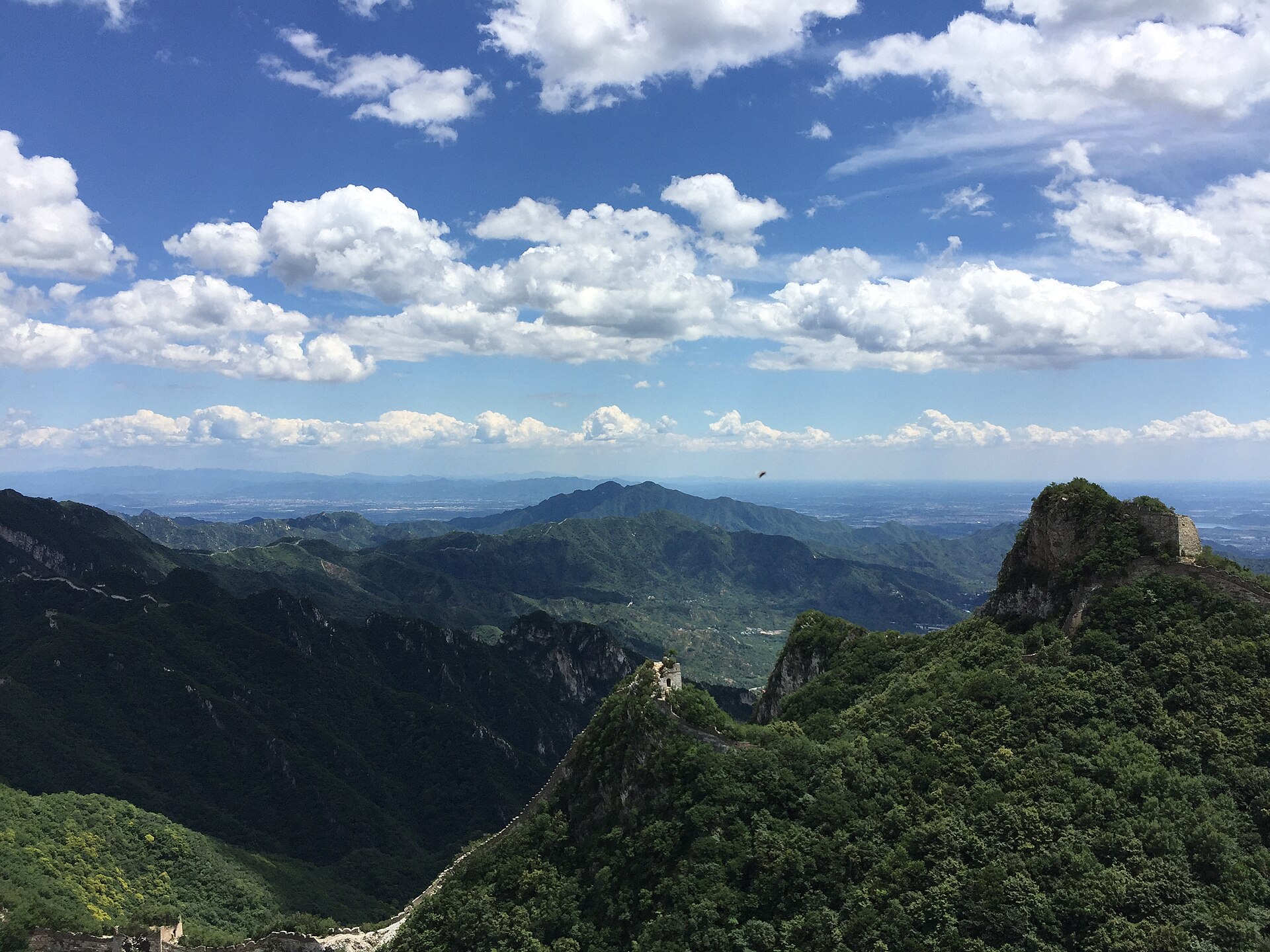 Ruined watchtowers of the unrestored Jiankou Great Wall on knife-edge green ridges above a wide valley