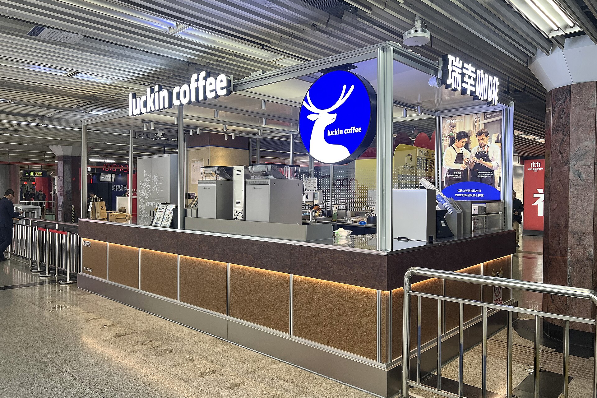 A Luckin Coffee kiosk with a white deer logo in a subway station concourse in Beijing