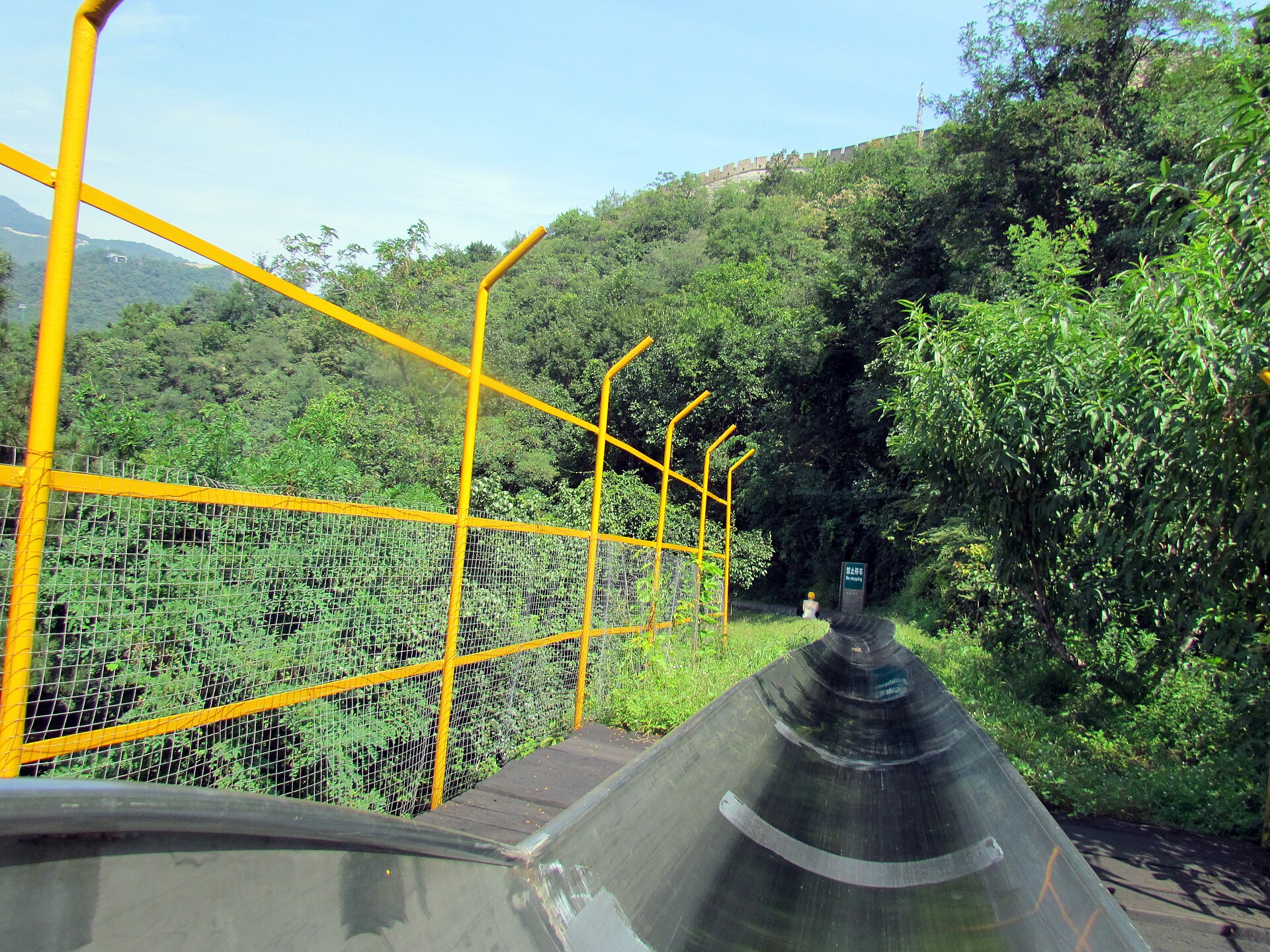 The metal toboggan chute running down through trees from the Mutianyu Great Wall, seen from a sled
