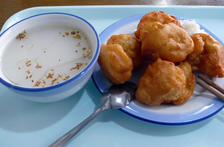 Almond jelly and golden fried cakes sit on a blue tray with a spoon and chopsticks at Wei's Yoghurt in Beijing.