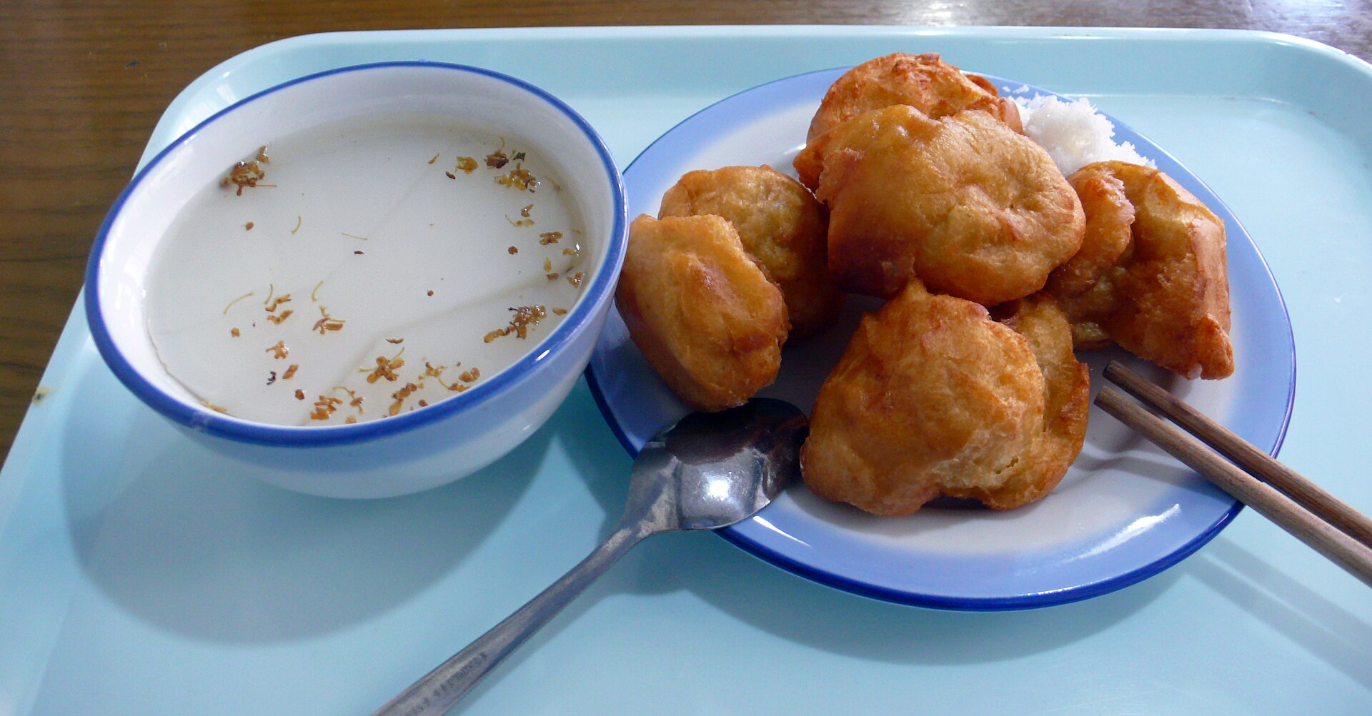 Almond jelly and golden fried cakes sit on a blue tray with a spoon and chopsticks at Wei's Yoghurt in Beijing.