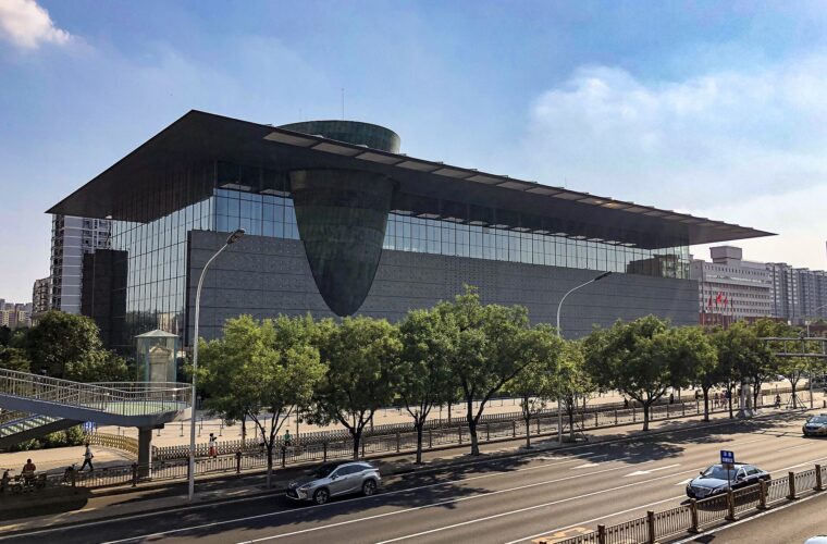 The Capital Museum in Beijing, a glass-walled building under a wide overhanging roof, with a bronze-clad drum tilting out through the facade