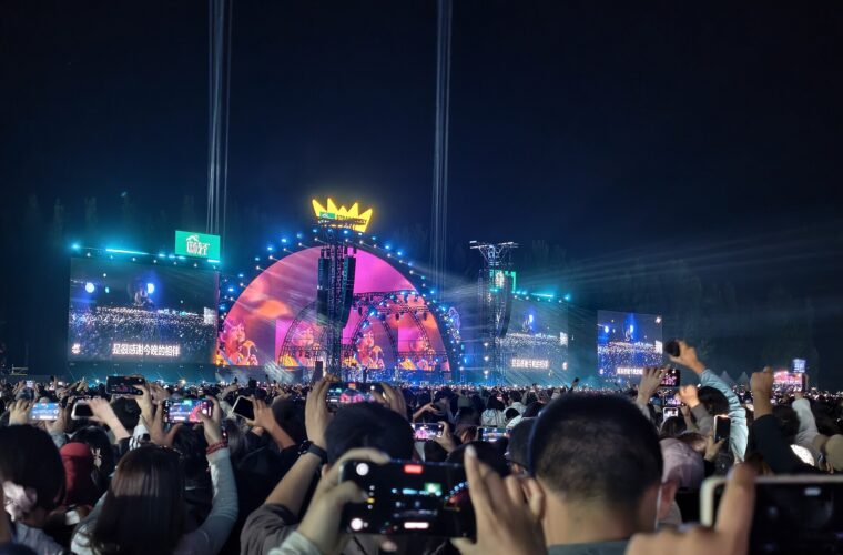 A crowd raises phones toward a brightly lit stage at the 2026 Beijing Super Strawberry Music Festival after dark.