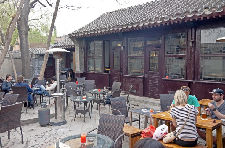 Customers drink beer at courtyard tables beside a tiled-roof building at Great Leap Brewing in Beijing.