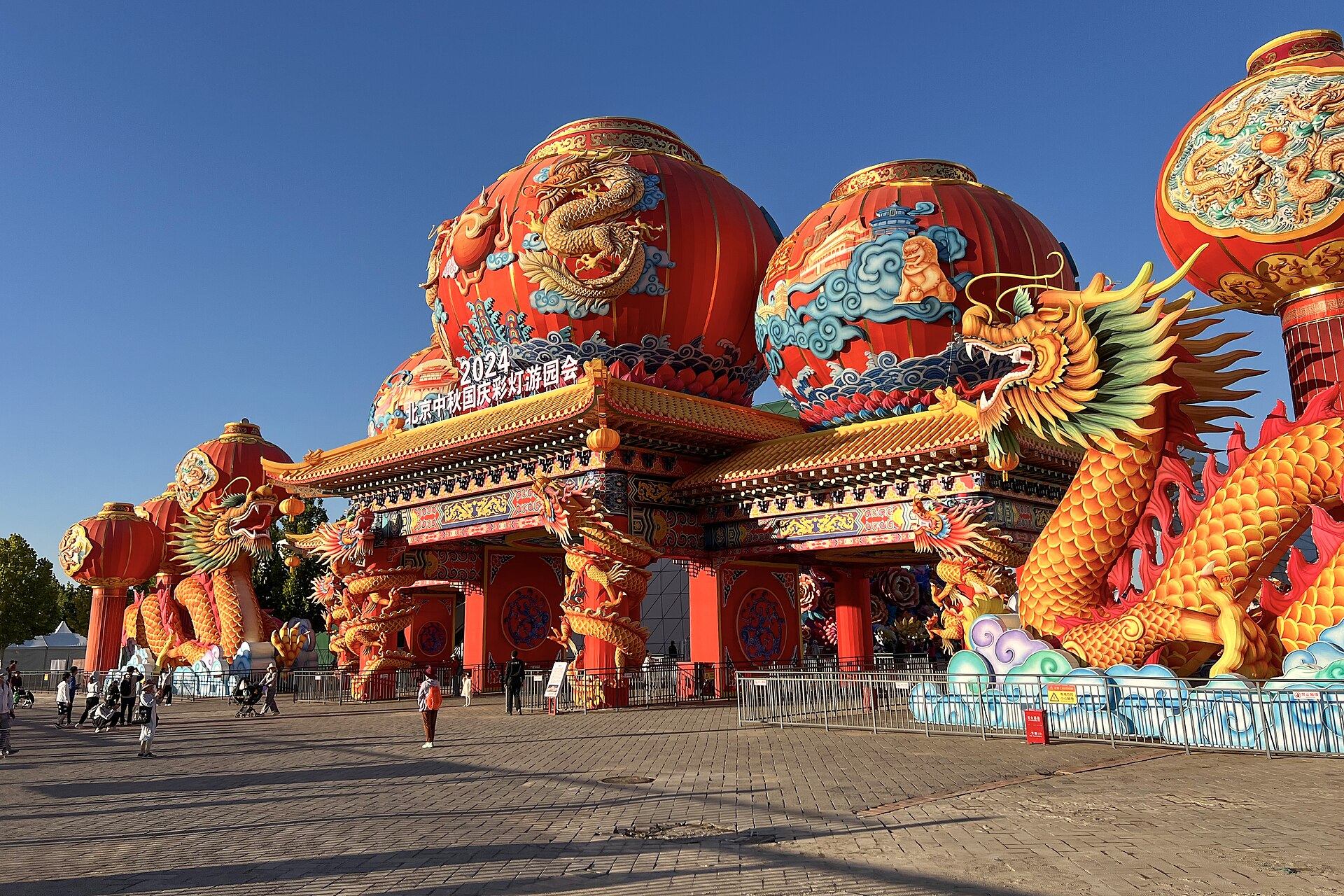 Giant red lanterns and golden dragons decorate the Jingcai Lantern Festival entrance at Beijing Garden Expo Park as visitors pass.