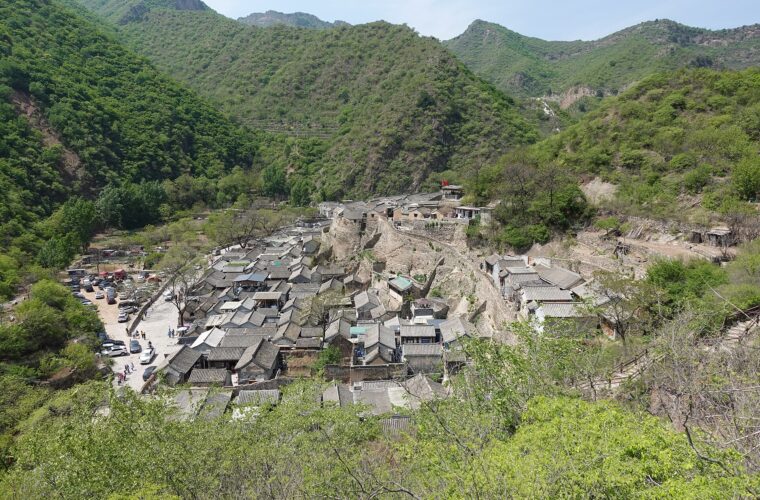 Grey tiled courtyard houses climb the green hillside at Cuandixia village, surrounded by steep mountains west of Beijing.