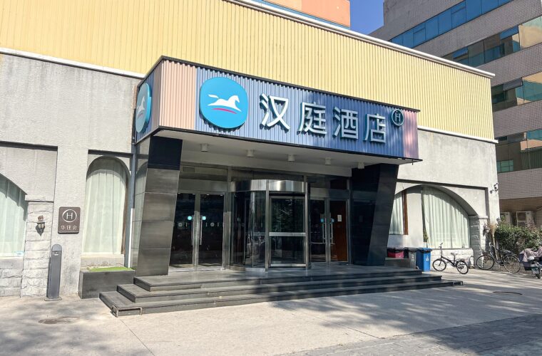Hanting Beijing Shangdi Hotel's blue horse logo and Chinese sign sit above a revolving glass entrance and broad steps.