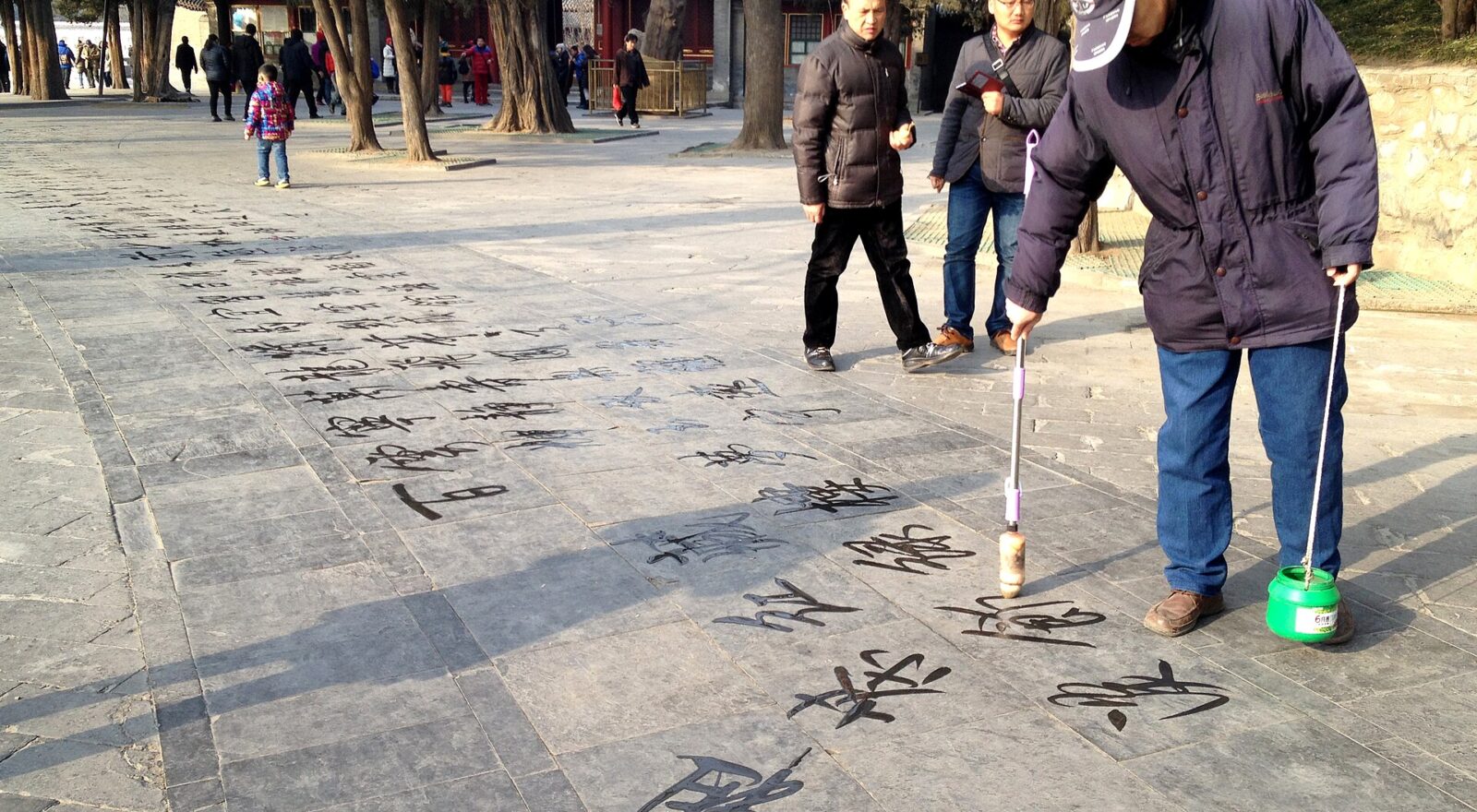 A man writes Chinese characters with a long water brush on paving at the Summer Palace in Beijing.