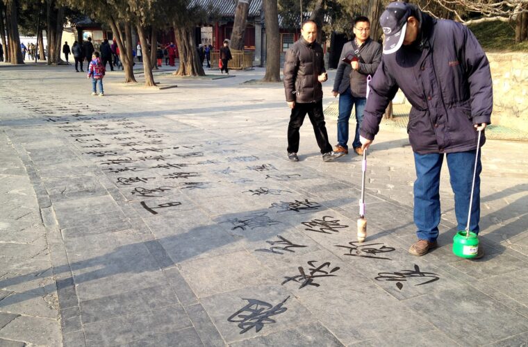A man writes Chinese characters with a long water brush on paving at the Summer Palace in Beijing.