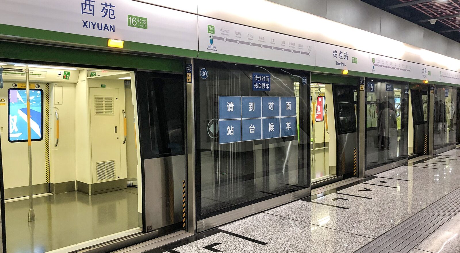 Open train doors line the Beijing Subway platform at Xiyuan, beneath bilingual station labels and green Line 16 signs.