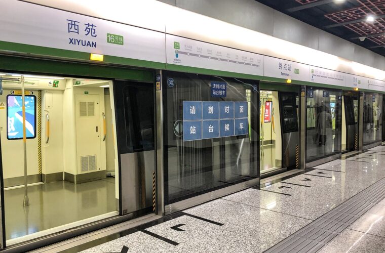 Open train doors line the Beijing Subway platform at Xiyuan, beneath bilingual station labels and green Line 16 signs.
