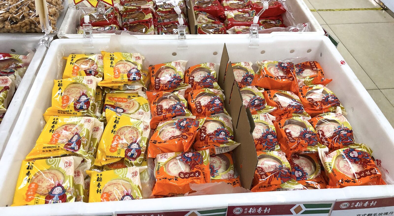 Packaged mooncakes fill labeled trays at a Beijing Daoxiangcun shop in Xibeiwang, with yellow and orange wrappers.
