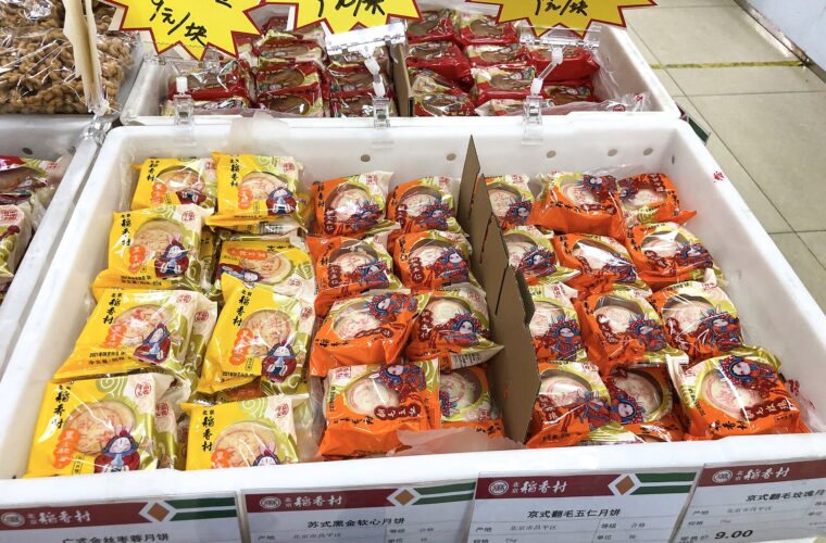 Packaged mooncakes fill labeled trays at a Beijing Daoxiangcun shop in Xibeiwang, with yellow and orange wrappers.