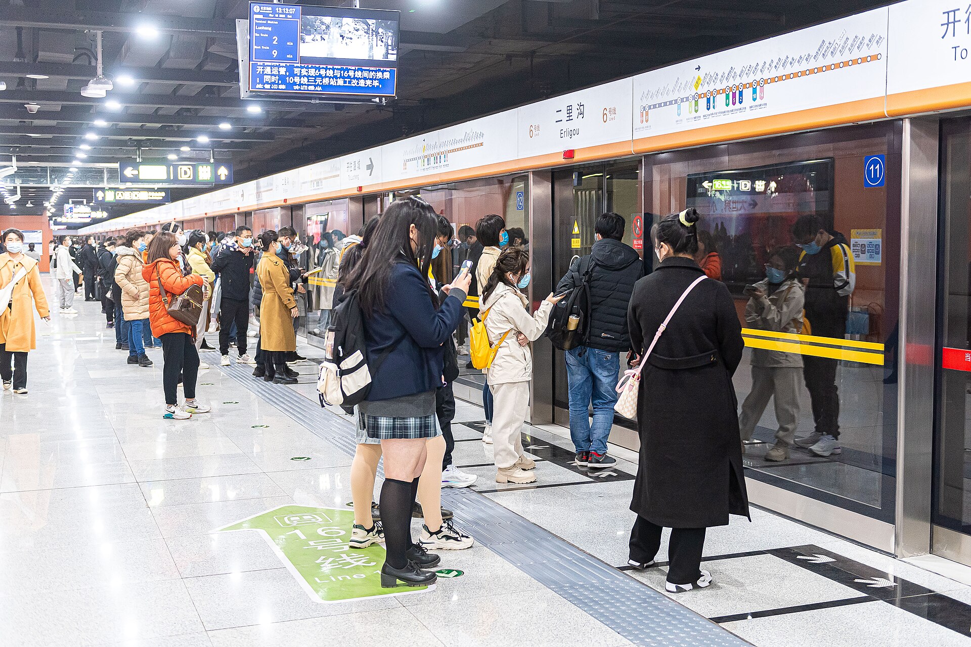Passengers wait behind platform screen doors at Erligou station on Beijing Subway Line 6 beneath bilingual station signs.