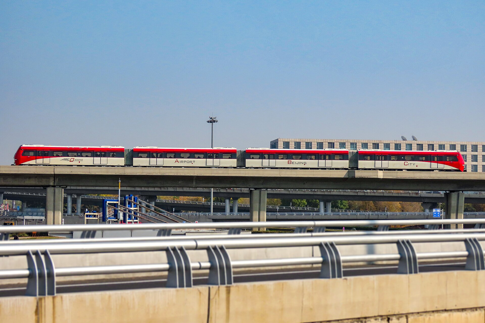 A red and cream Capital Airport Express train crosses elevated tracks outside Terminal 3 at Beijing Capital Airport.