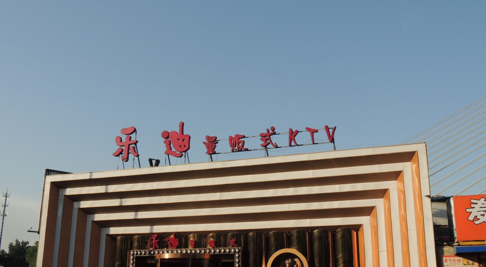 Red Ledi KTV lettering tops a striped karaoke venue entrance in Beijing Shangdi, with pedestrians and a parked red car.