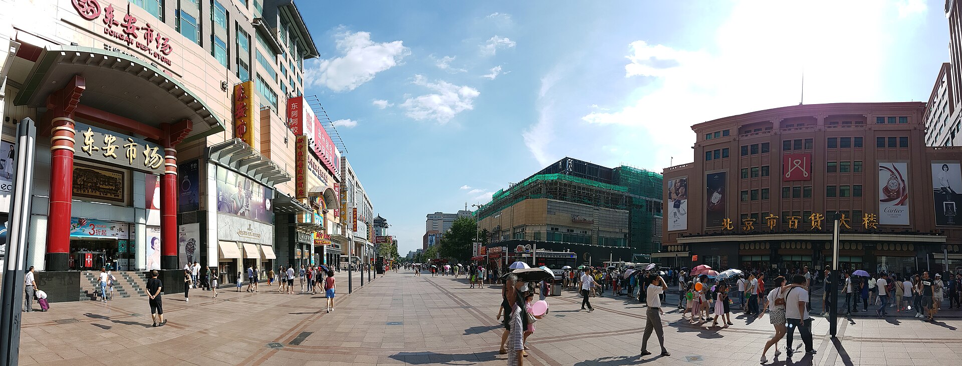 Shoppers walk along Beijing's broad Wangfujing pedestrian street between Dong'an Market and the Beijing Department Store under blue skies.