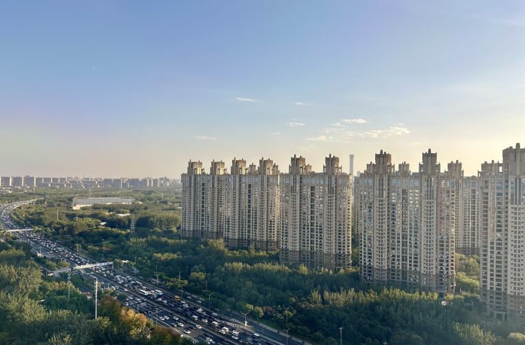 Tall apartment blocks at 8 Xiaoyun Road in Beijing stand above trees beside a curving road filled with traffic.
