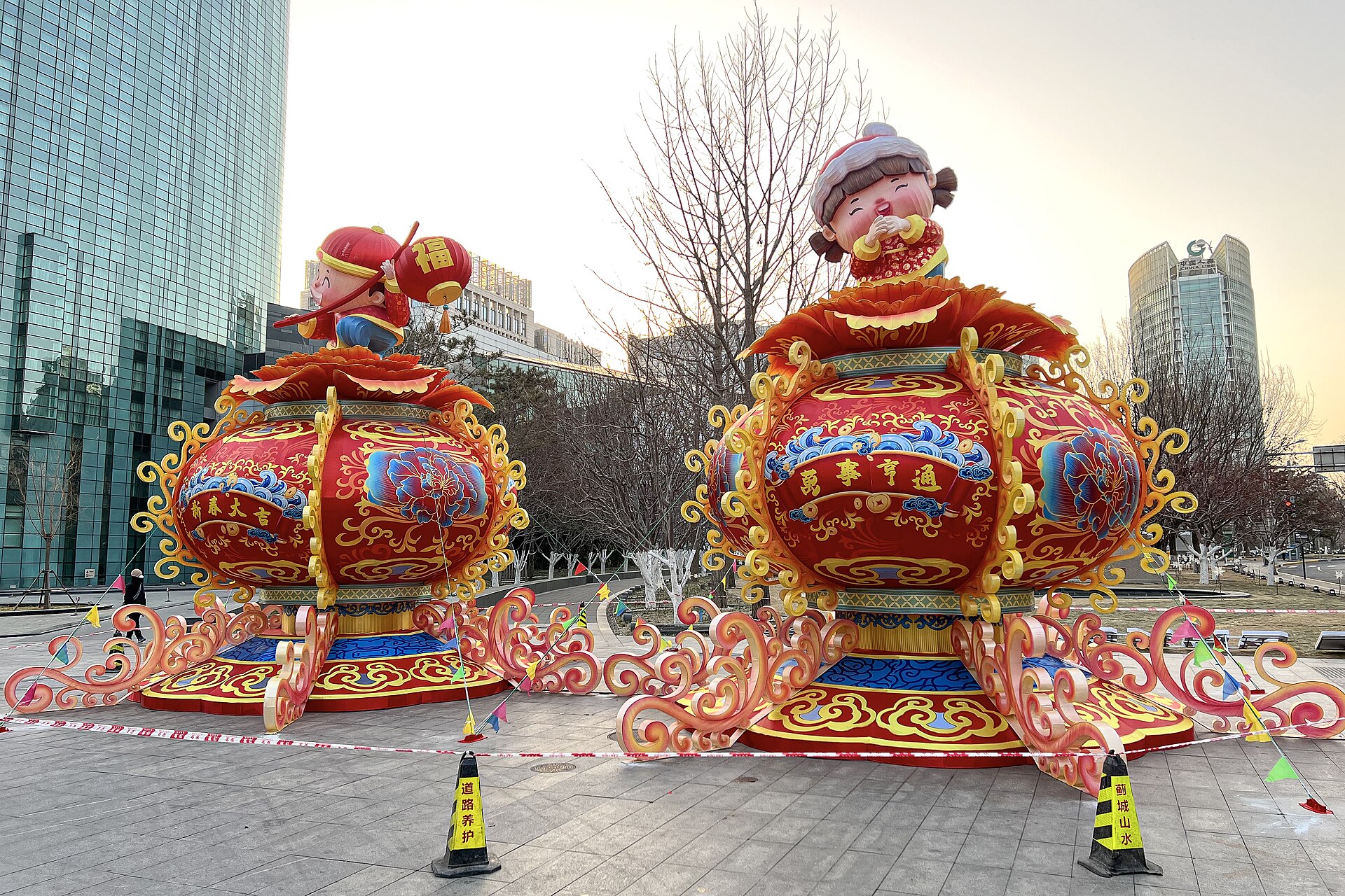 Two giant red and gold New Year lanterns topped by cartoon figures stand among office towers on Beijing Financial Street.