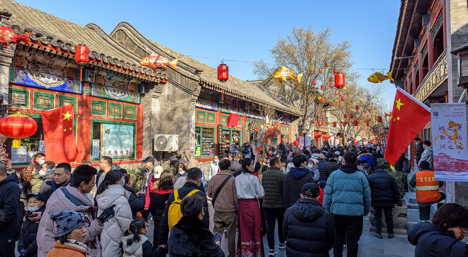 Visitors fill Liulichang East Street in Beijing beneath red lanterns and fish decorations during Changdian Temple Fair.