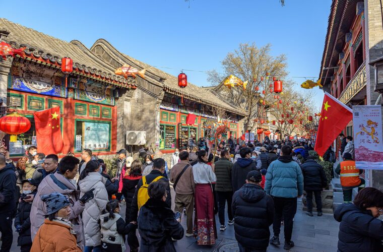 Visitors fill Liulichang East Street in Beijing beneath red lanterns and fish decorations during Changdian Temple Fair.