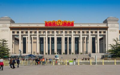 Visitors wait behind barriers outside the columned west entrance of the National Museum of China in Beijing beneath a clear sky.