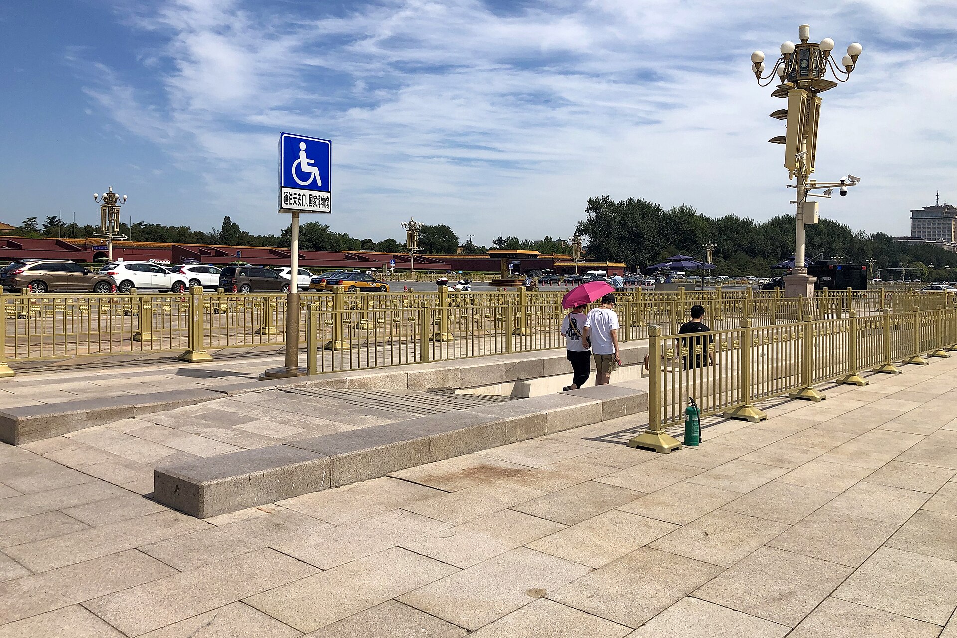 A wheelchair sign marks a stone ramp beside steps and gold railings at Tiananmen Square in Beijing.