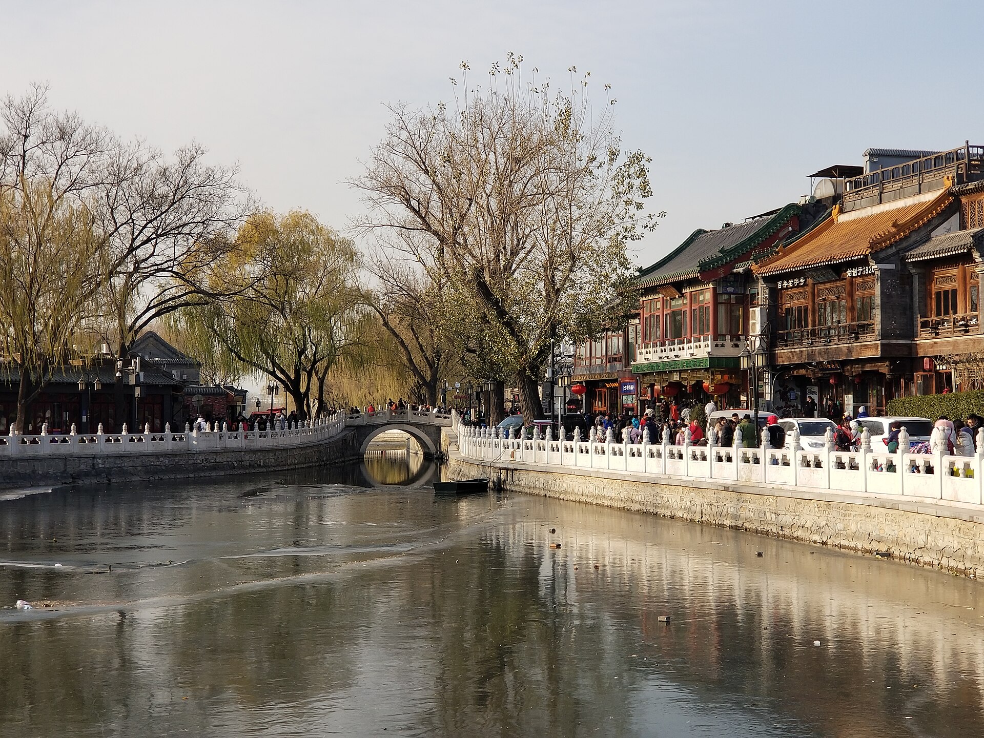 Yinding Bridge arches over Shichahai's water in Beijing, framed by willows, white balustrades and a busy lakeside promenade.