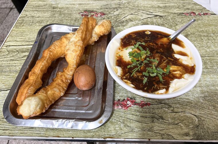 Youtiao fried dough sticks, a tea egg and savory tofu pudding form a breakfast at Xixinlitun in Beijing.